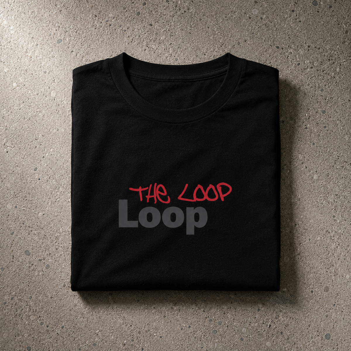 Folded black Loop Tee showing THE LOOP handstyle over charcoal Loop